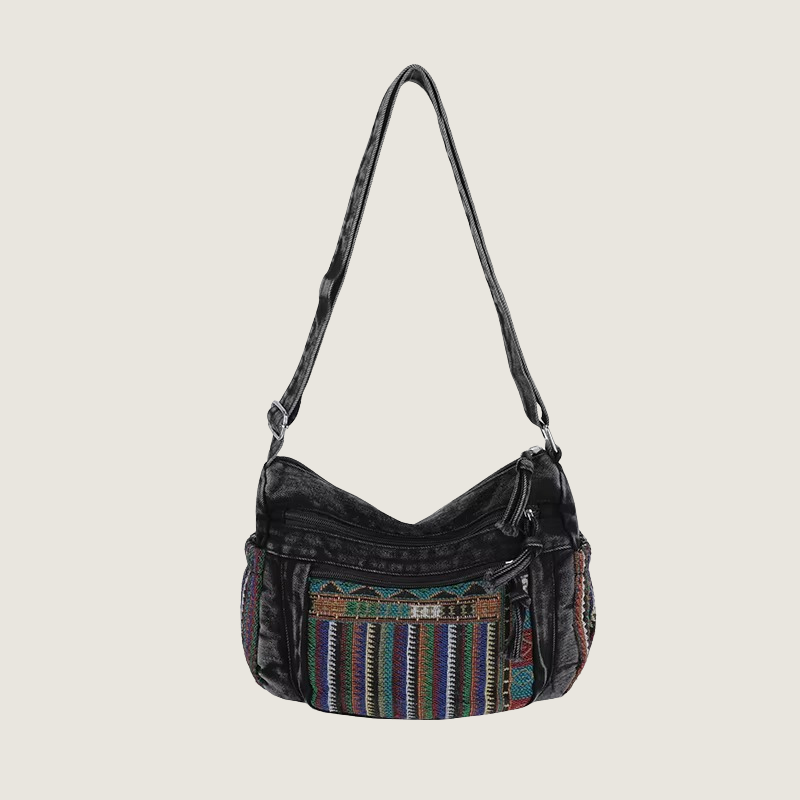 Bolsa boho feminina em denim com bordado étnico colorido, versátil para uso no ombro ou transversal.